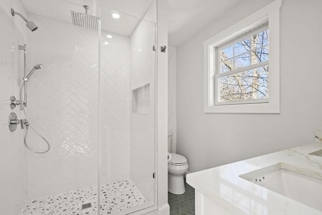 bathroom featuring a sink, double vanity, a stall shower, toilet, and recessed lighting