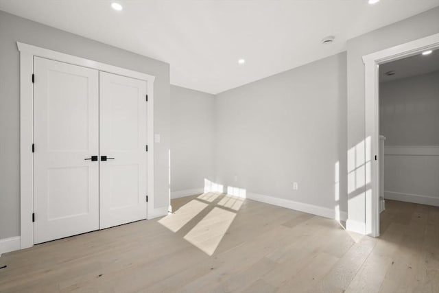 unfurnished bedroom featuring recessed lighting, baseboards, light wood-style floors, and a closet
