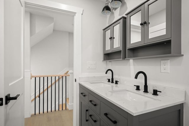 bathroom with double vanity, wood finished floors, and a sink