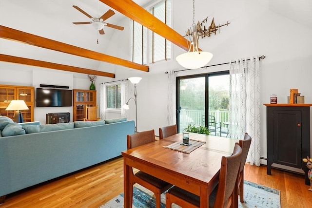 dining space featuring high vaulted ceiling, ceiling fan, light wood-style flooring, and beam ceiling