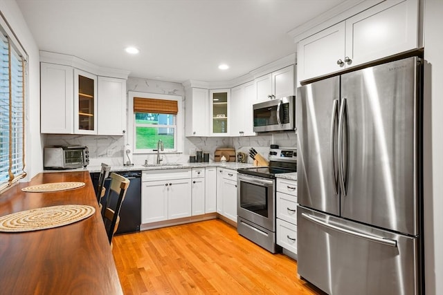 kitchen with stainless steel appliances, a sink, tasteful backsplash, white cabinetry, and recessed lighting
