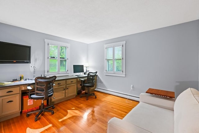 office area with a baseboard heating unit, plenty of natural light, light wood-style floors, and built in study area