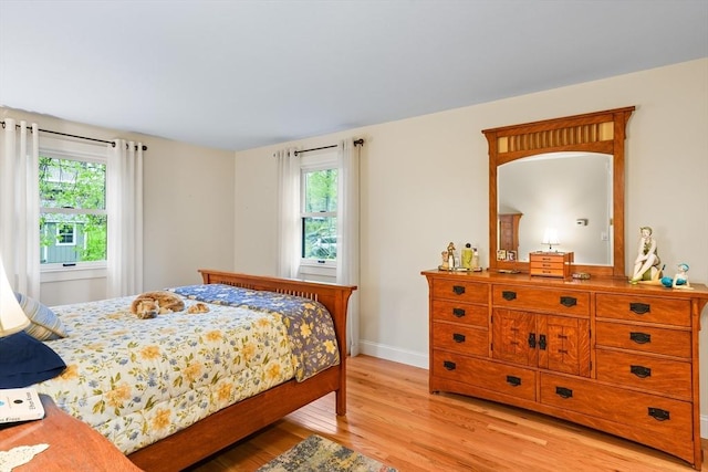 bedroom featuring light wood finished floors, multiple windows, and baseboards