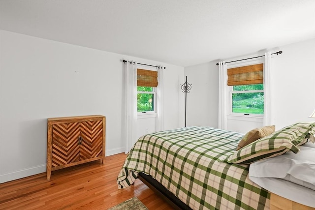 bedroom featuring multiple windows, wood finished floors, and baseboards