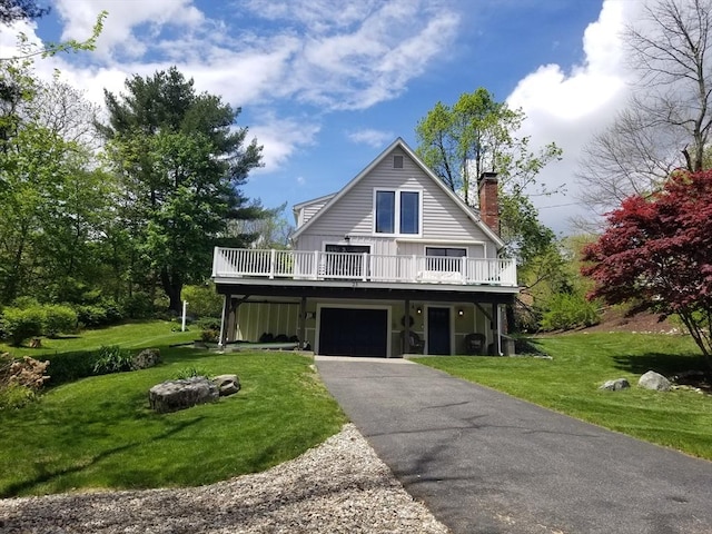 view of front of property with a chimney, a front lawn, a wooden deck, asphalt driveway, and an attached garage