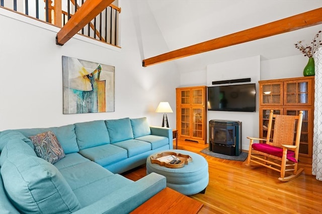 living room with a wood stove, high vaulted ceiling, and wood finished floors