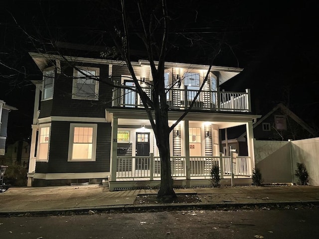 view of front of home featuring covered porch, fence, and a balcony