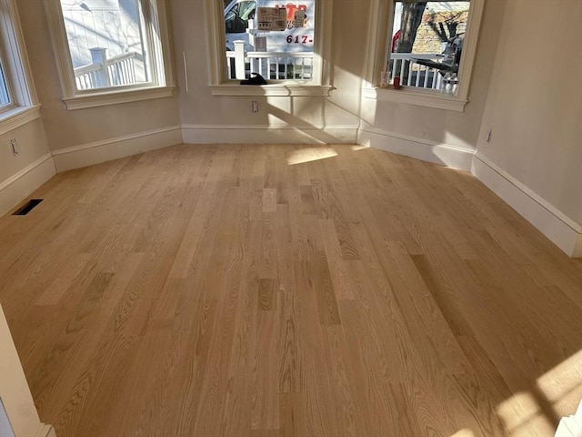 unfurnished dining area featuring visible vents, plenty of natural light, baseboards, and wood finished floors