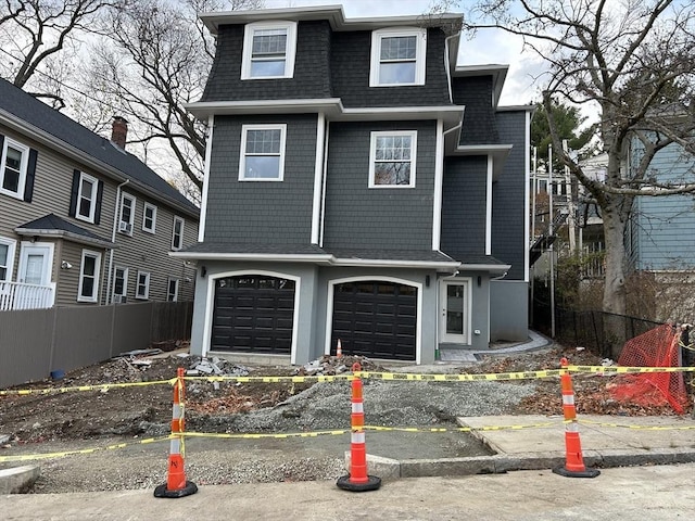 view of front of property with fence, roof with shingles, mansard roof, a garage, and driveway