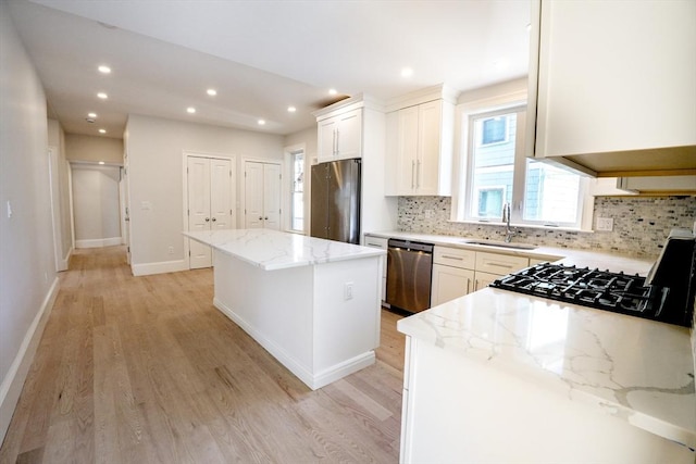 kitchen featuring a sink, light stone counters, a kitchen island, and stainless steel appliances