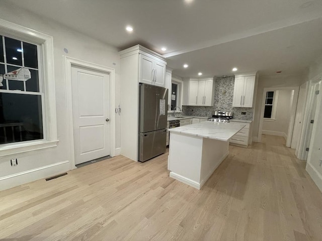 kitchen featuring white cabinets, light wood finished floors, visible vents, and freestanding refrigerator