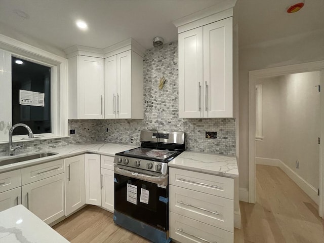 kitchen with light wood finished floors, white cabinets, stainless steel stove, and a sink