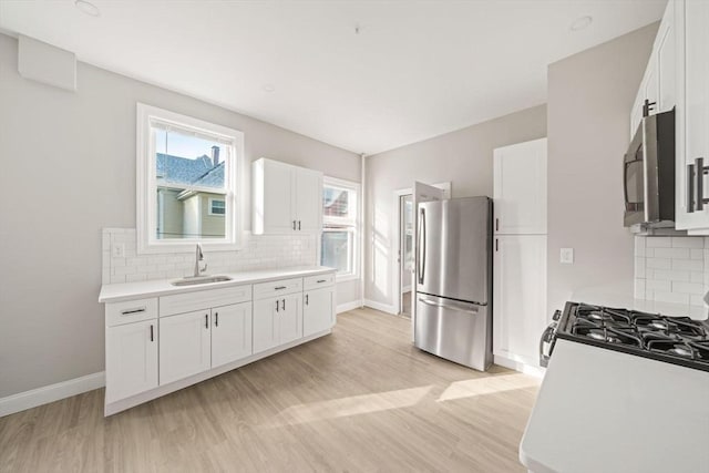 17 Magnolia Sq, Boston, MA 02125 - kitchen featuring stainless steel appliances, a sink, decorative backsplash, baseboards, and white cabinets