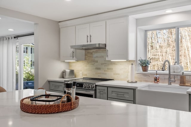 kitchen featuring gray cabinetry, white cabinetry, stainless steel electric range oven, sink, and light stone countertops