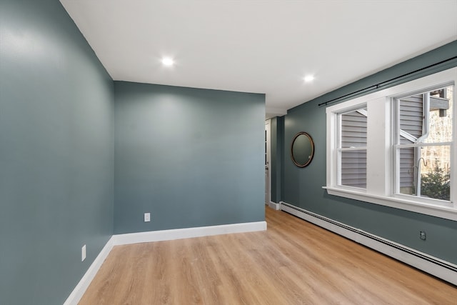 empty room with light wood-type flooring and a baseboard heating unit