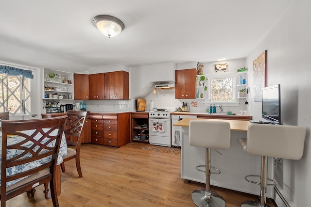 kitchen with white range, a baseboard heating unit, kitchen peninsula, light hardwood / wood-style floors, and decorative backsplash