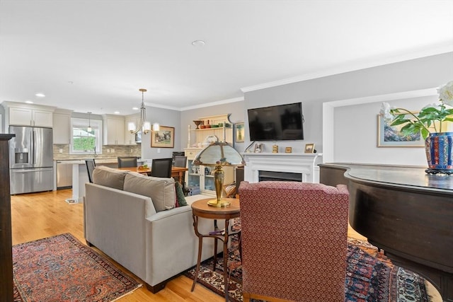 2 Heron Way Unit B, Salisbury, MA 01952 - living area featuring ornamental molding, a chandelier, light wood-style flooring, a fireplace, and recessed lighting
