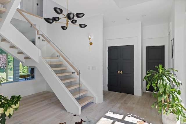 entrance foyer with a notable chandelier, wood finished floors, baseboards, and stairs