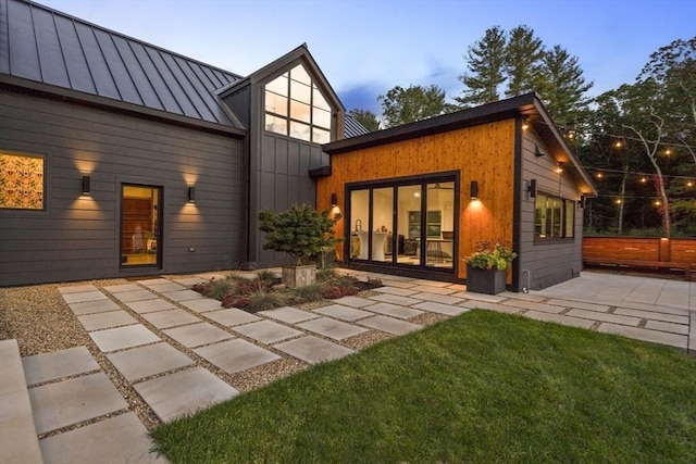 back of house with a yard, metal roof, a standing seam roof, and a patio