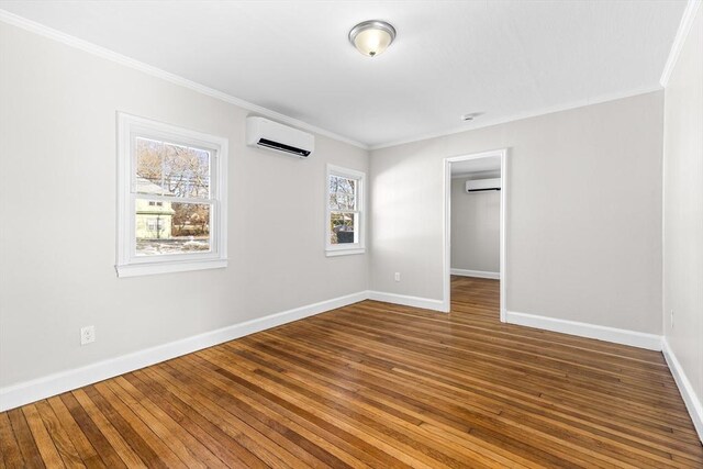 spare room featuring hardwood / wood-style floors, a wall unit AC, and a healthy amount of sunlight