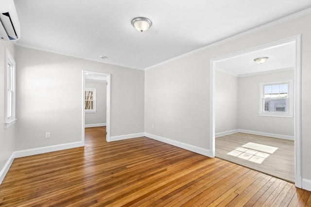 unfurnished room with crown molding, hardwood / wood-style floors, and an AC wall unit