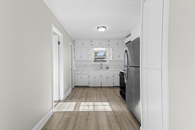 kitchen with sink, stainless steel fridge, a barn door, light hardwood / wood-style floors, and white cabinets