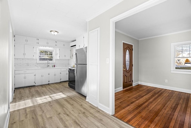 kitchen featuring white cabinetry, tasteful backsplash, stainless steel refrigerator, and light wood-type flooring