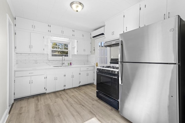 kitchen with gas stove, sink, white cabinets, and stainless steel refrigerator