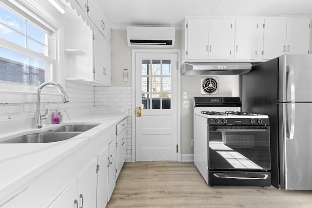 kitchen with sink, extractor fan, a wall mounted air conditioner, gas range oven, and white cabinets