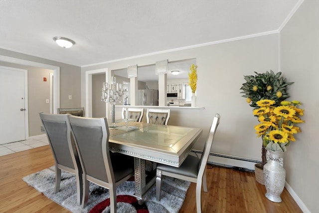 dining area featuring crown molding, baseboard heating, and light wood-type flooring