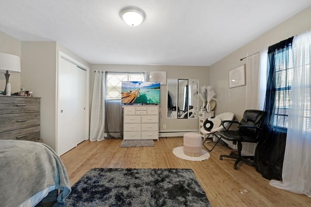 bedroom with multiple windows, a baseboard radiator, and light hardwood / wood-style flooring