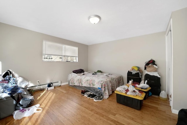 bedroom with hardwood / wood-style floors and a baseboard heating unit