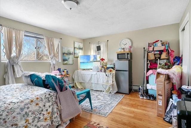 bedroom with a closet, light hardwood / wood-style flooring, and stainless steel refrigerator