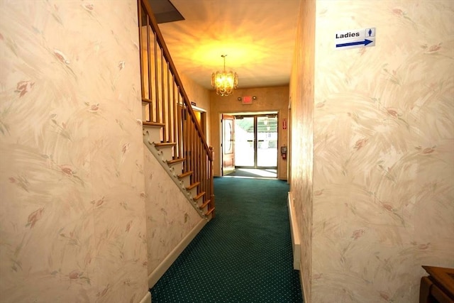 corridor with dark carpet and an inviting chandelier