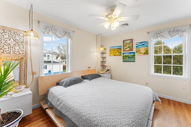 bedroom with multiple windows, ceiling fan, and hardwood / wood-style floors