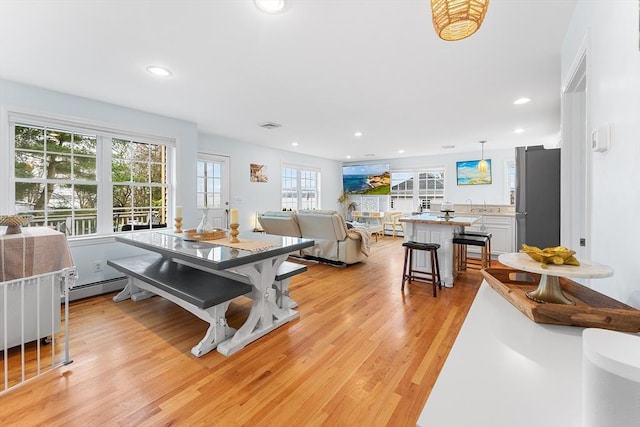 dining space with light hardwood / wood-style flooring and a baseboard heating unit