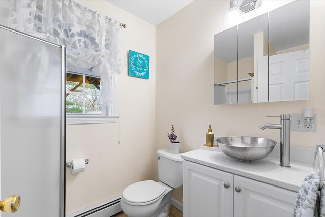 bathroom featuring walk in shower, vanity, toilet, and baseboard heating