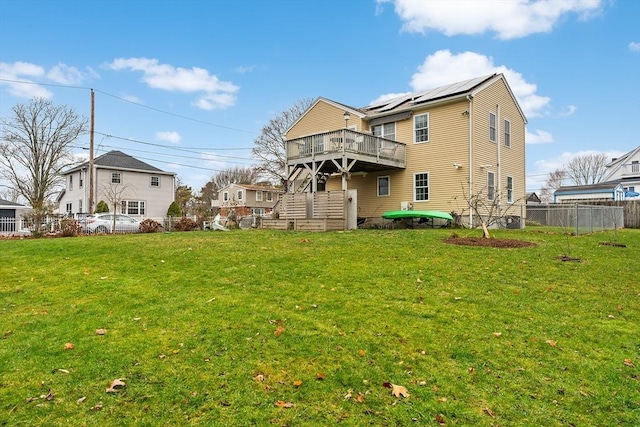 back of house featuring solar panels, a yard, and a wooden deck