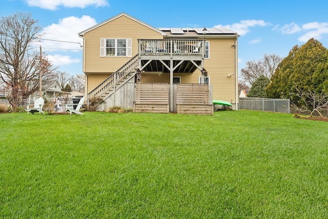 back of property with solar panels, a lawn, and a wooden deck