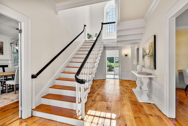 entrance foyer featuring ornamental molding, stairway, and light wood-style flooring