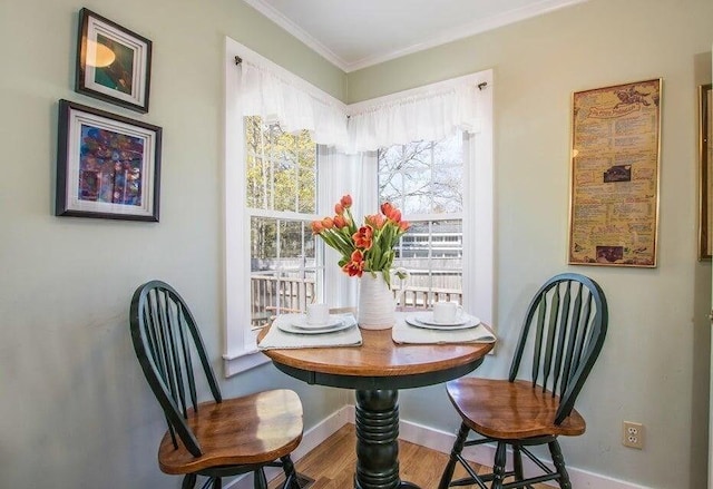 dining space featuring crown molding, baseboards, and wood finished floors