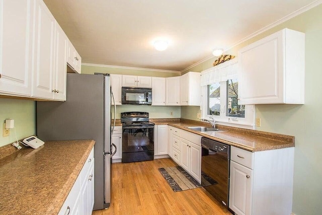kitchen with white cabinets, light wood-type flooring, black appliances, and a sink