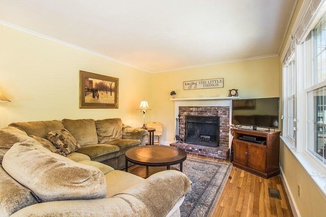 living room with a fireplace, ornamental molding, visible vents, and wood finished floors
