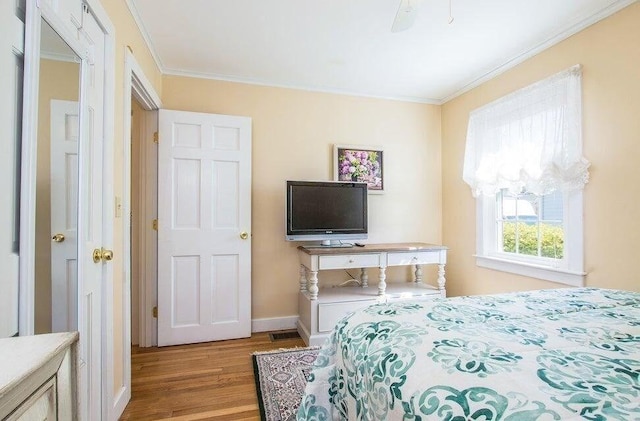 bedroom featuring wood finished floors, baseboards, and ornamental molding