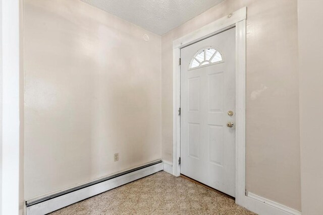 carpeted foyer entrance with a textured ceiling and a baseboard radiator