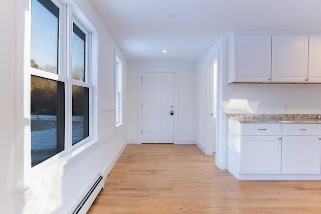 corridor with baseboard heating and light hardwood / wood-style flooring