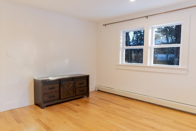 unfurnished room with baseboard heating and light wood-type flooring