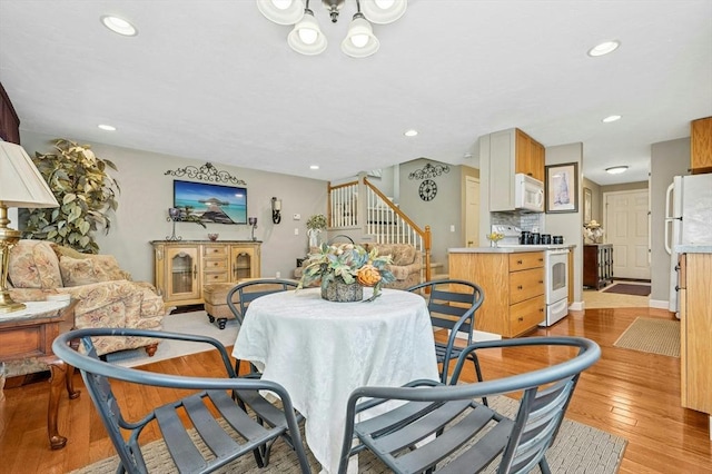 dining space with recessed lighting, stairs, a notable chandelier, and light wood-type flooring
