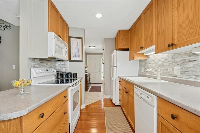 kitchen with white appliances, light countertops, light wood-style flooring, and a sink
