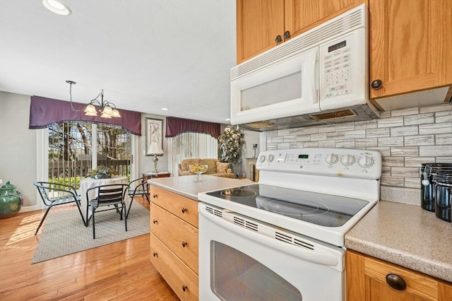 kitchen featuring light wood finished floors, light countertops, and white appliances